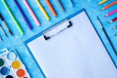 Boya aletlerinin bileşimi. Kalemler, kalemler, fırçalar, boyalar ve kağıt. Mavi arkaplan