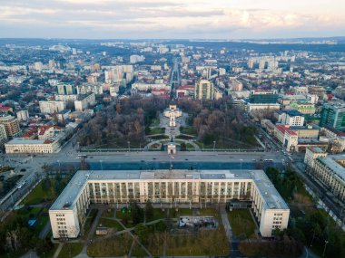 Chisinau 'nun günbatımında hava aracı görüntüsü. Şehir merkezinin panorama manzarası, Hükümet Binası ve Central Park, birden fazla bina, hareket eden arabalı yollar, çıplak ağaçlar. Moldova