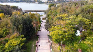 Chisinau Cascade merdivenlerinin hava aracı görüntüsü. Çok sayıda yeşil ağaç, yürüyen insanlar, arka planda göl. Moldova