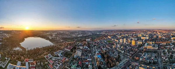 Aerial drone view of Chisinau at sunset. Panorama view of multiple buildings, bare trees, park, lake and clear sky. Moldova