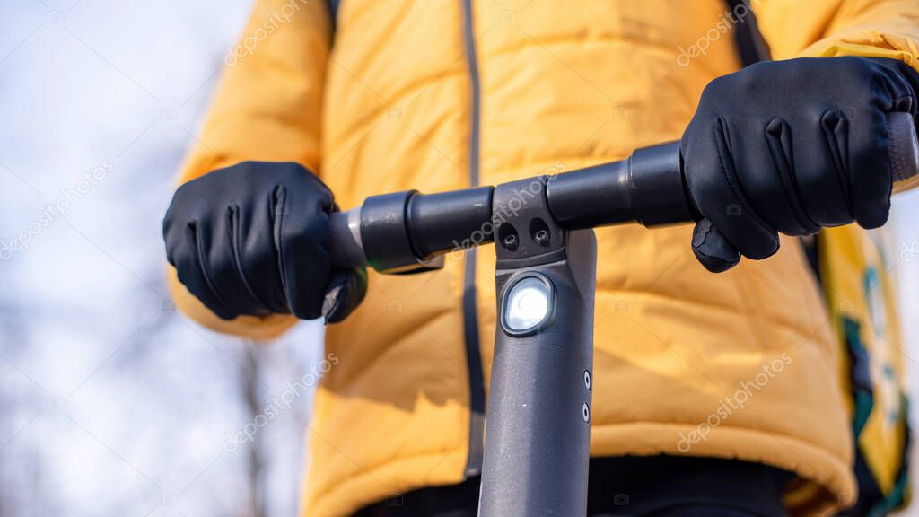 Food delivery man on a scooter. Yellow jacket. Winter, trees on the background