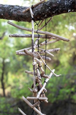 Yunanistan 'da bir ormanda ağaç dalına asılı ahşap bir kolye, arka planda yeşillik.