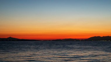 Ege Denizi 'nde gün batımı, uzakta ışıklar ve kara, su ve Yunanistan