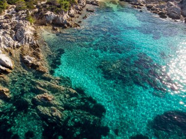Kıyıya yakın kayalıkları ve mavi şeffaf suyun altındaki Ege kıyısı, Yunanistan insansız hava aracı manzaralı