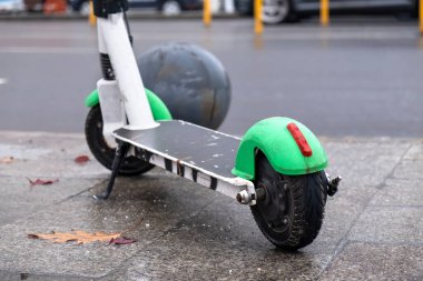 Romanya 'nın Bükreş kentinde hareket halindeki arabalarla, yağmurlu ve bulutlu havayla yol kenarında park halindeki elektrikli scooter' ın yakın çekimi