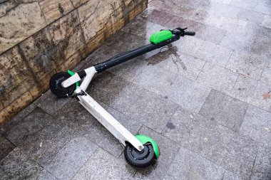 Romanya 'nın Bükreş kentinde bulutlu havada ıslak zeminde paylaşmak için elektrikli scooter kullanılıyor