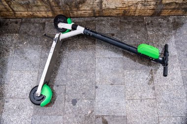 Romanya 'nın Bükreş kentinde bulutlu havada ıslak zeminde paylaşmak için elektrikli scooter kullanılıyor