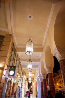 SALONIKI, GREECE - 26 Ekim 2020: Gece yarısı Electra Palace Oteli, binanın birinci katındaki gece lambaları, yürüyen insanlar ve mağazalar