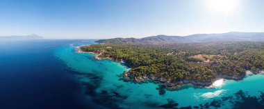 Ege kıyılarının geniş açılı görüntüsü mavi şeffaf su, çevrede yeşillik, insansız hava aracı Pamorama manzarası, Yunanistan