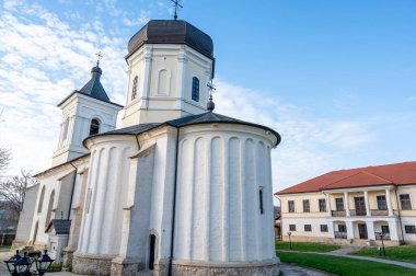 Capriana manastırının iç sarayındaki Taş Kilisesi. Çıplak ağaçlar, yeşil çimenler ve binalar, Moldova 'da güzel hava.