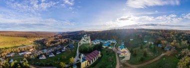 Panorama shot of the Hancu Monastery from the drone. Churches, other buildings and green lawns. Hills with bare and yellowed trees near it. Moldova clipart