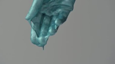 Kapalı kadın elleri turkuaz boyalarla oynuyor, yavaş çekim.