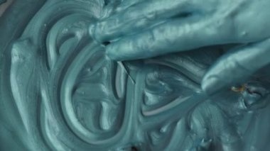 Kapalı kadın elleri turkuaz boyalarla oynuyor, yavaş çekim.