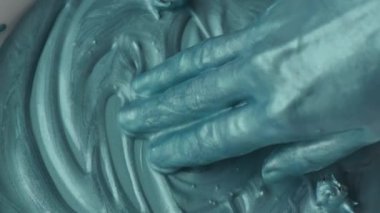 Kapalı kadın elleri turkuaz boyalarla oynuyor, yavaş çekim.