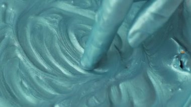 Kapalı kadın elleri turkuaz boyalarla oynuyor, yavaş çekim.