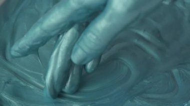 Kapalı kadın elleri turkuaz boyalarla oynuyor, yavaş çekim.