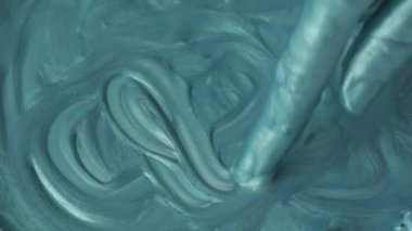 Kapalı kadın elleri turkuaz boyalarla oynuyor, yavaş çekim.