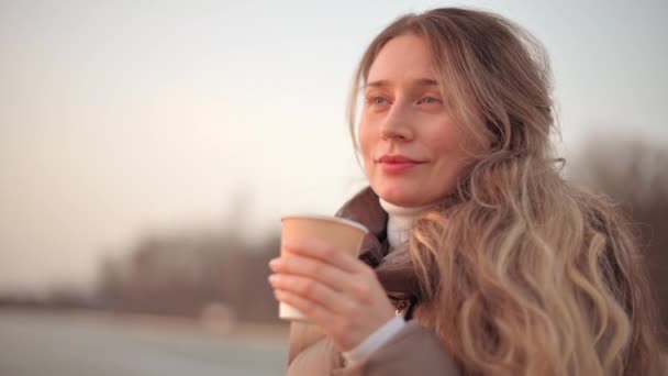 Happy smiling woman drinking a cup of coffee at sunset — Stock Video