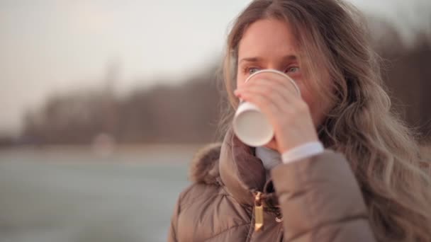 Šťastná usměvavá žena pije šálek kávy při západu slunce — Stock video