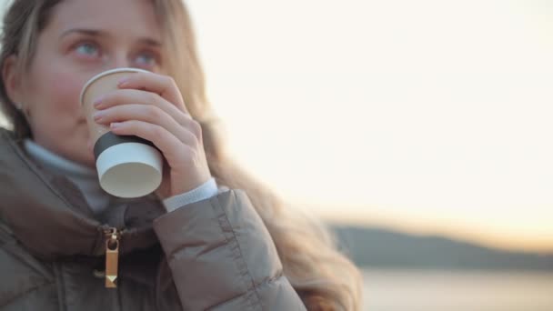 Щаслива усміхнена жінка п'є чашку кави на заході сонця — стокове відео