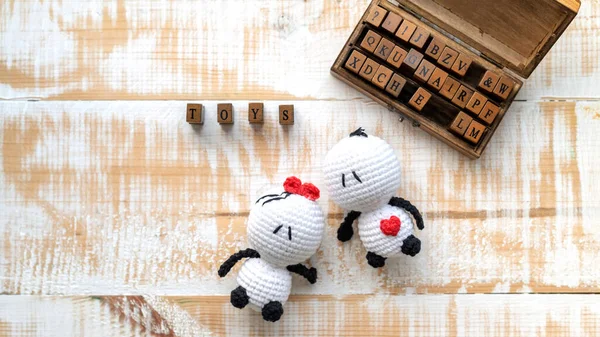 Two handmade knitted toys and wooden set of letters composing word. Top view