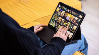 CHISINAU, MOLDOVA - 27 HAZİRAN 2021: Genç kız Netflix 'te bir filmi kanepesinde seçiyor