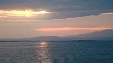 Yunanistan 'da Ege Denizi' nin suyundan gün batımı manzarası. Turuncu gökyüzü, bulutlu hava