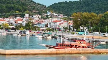 THASOS, GREECE - 23 Eylül 2020: Ege kıyısı manzarası, demirli tekneler ve tepenin altındaki eski bir yat, yeşillik dolu tepenin altı