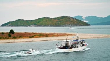 THASOS, GREECE - 23 Eylül 2020: kaynayan suyla dolu bir tekne taşıyan römorkör. Tepeler arka planda. Bulutlu hava, gün batımı