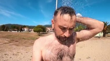 Asprovalta sahilinde duş alan adam, arka planda şehir, Yunanistan