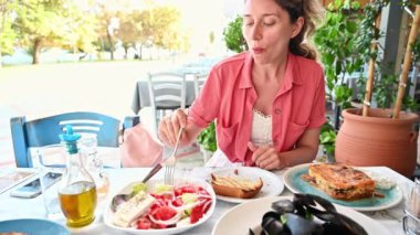 Restoranda yemek yiyen bir kadın, Akdeniz yemekleriyle dolu birden fazla tabak, Asprovalta, Yunanistan