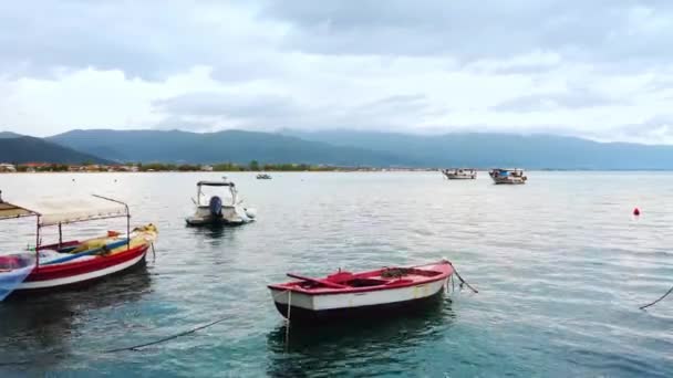 Förtöjda Båtar Stranden Egeiska Havet Stad Och Kullar Bakgrunden Molnig — Stockvideo