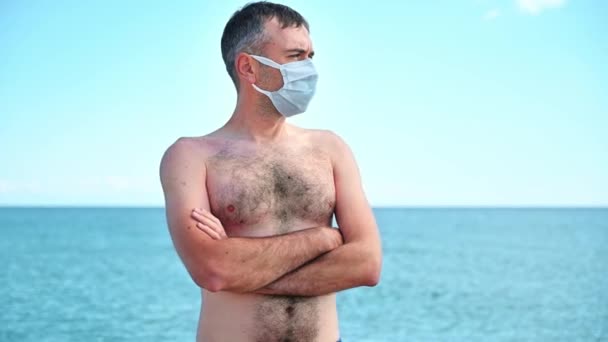 ギリシャのエーゲ海沿岸の白い医療マスクの男の肖像 背景の水 — ストック動画