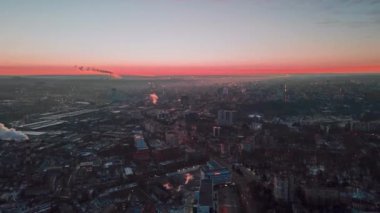 Chisinau 'nun günbatımında, insansız hava aracı görüşü. Birden fazla bina, hareket eden arabalı yollar, borulardan çıkan duman. Moldova