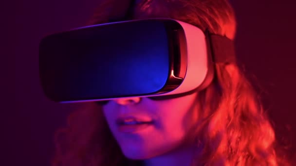 使用彩色霓虹灯的虚拟现实耳机的年轻姜黄发女郎 — 图库视频影像