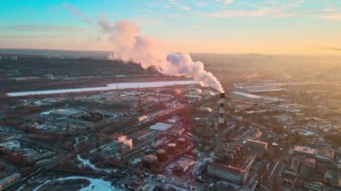 Chisinau 'nun güneş doğarken hava aracı görüntüsü. Tüpten çıkan dumanlı termal istasyon. Binalar, yollar ve çıplak ağaçlar. Hava güzel, yerde kar var. Moldova