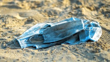 Gölün sahilinde bir grup kirli tıbbi maske. Kirlilik fikri