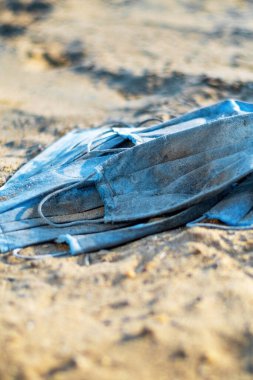 Gölün sahilinde bir grup kirli tıbbi maske. Kirlilik fikri