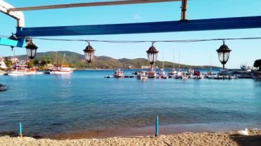Askıya alınmış sokak lambaları, demirlemiş yelkenliler ve arka plandaki kasaba manzarası, Yunanistan 'ın Neos Marmaras kenti. Yavaş çekim