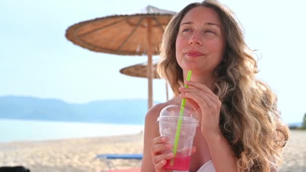 Mujer Caucásica Tomando Cóctel Rojo Playa Mar Sombrillas Movimiento Lento — Vídeo de stock