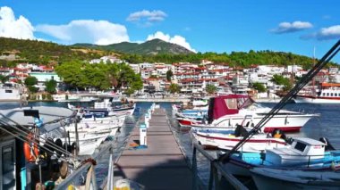 NEOS MARMARMARAS, GREECE - 8 Ekim 2020: Birden fazla demirlemiş yat ve teknesi olan Ege limanı, ahşap iskele, yeşil, açık hava koşulları olan bir tepenin üzerinde yer alan kasaba