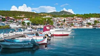 NEOS MARMARMARAS, GREECE - 8 Ekim 2020: Birden fazla demirlemiş yat ve teknesi olan Ege limanı, ahşap iskele, yeşillik ve açık hava olan bir tepenin üzerinde yer alan kasaba. Yavaş çekim