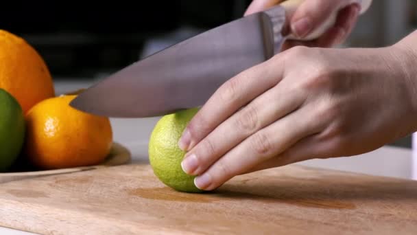 Frau Schneidet Kalk Zwei Teile Auf Einem Holzbrett Früchte Hintergrund — Stockvideo