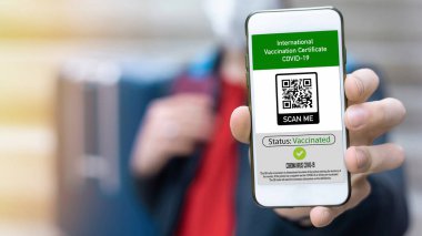 Akıllı telefonda Uluslararası Aşı Sertifikası COVID-19 QR kodu gösteren bir adam
