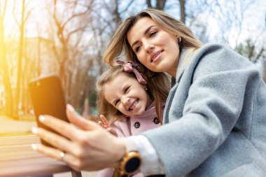 Mutlu anne ve kız dışarıda selfie çekiyor.