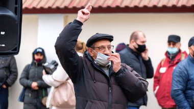CHISINAU, MOLDOVA - 28 Nisan 2021: Sağlık maskeli yaşlı bir adam el kaldırdı, insanlar anayasa mahkemesi binası önünde erken seçimleri protesto ediyorlar