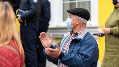 CHISINAU, MOLDOVA - 28 Nisan 2021: Sağlık maskeli yaşlı bir adam, Anayasa Mahkemesi binası önünde erken seçimleri protesto eden insanlar