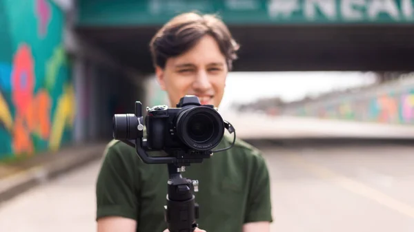 Młody Uśmiechnięty Fotograf Kamerą Statywie Podczas Sesji Zdjęciowej Drodze — Zdjęcie stockowe