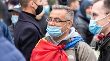 CHISINAU, MOLDOVA - 28 Nisan 2021: Tıp maskeli ve gözlüklü adam, Anayasa Mahkemesi binası önünde erken seçimleri protesto eden insanlar