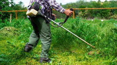 A man is working with hand-held lawn mower in the garden